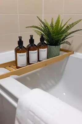 a shelf with four bottles of soap and a plant at Modern 2-Bed Townhouse in Kirkdale in Liverpool