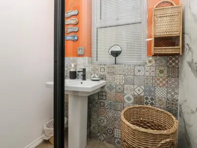 a bathroom with a white sink and a basket at West End Bay in Morecambe