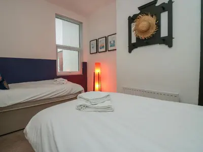 a bedroom with two beds and a light on a table at West End Bay in Morecambe