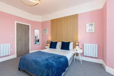 a bedroom with a large bed with pink walls at Beachfront Apartment 3 Bedrooms Sleeps 7 - Gateway to the Lake District - Newly Refurbished in Morecambe