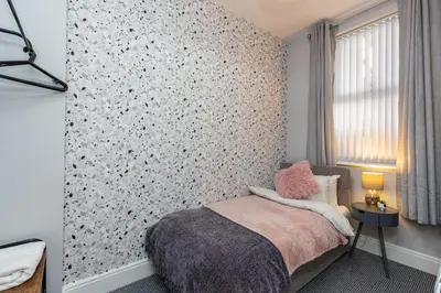 a bedroom with a wall covered in floral wallpaper at Beachfront Apartment 3 Bedrooms Sleeps 7 - Gateway to the Lake District - Newly Refurbished in Morecambe