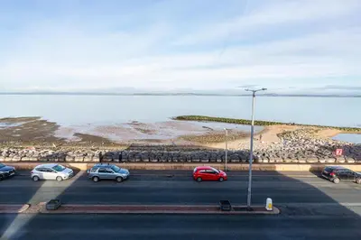 a parking lot with cars parked next to the water at Beachfront Apartment 3 Bedrooms Sleeps 7 - Gateway to the Lake District - Newly Refurbished in Morecambe