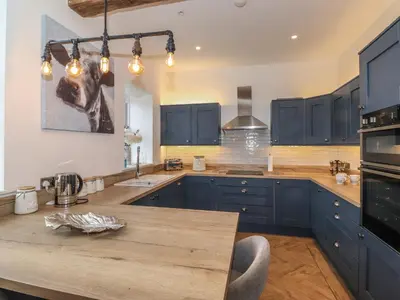 a kitchen with blue cabinets and a wooden counter top at Old Watermill in Grange Over Sands