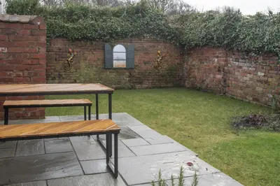 a backyard with two picnic tables and a brick wall at Botanic Mews in Southport