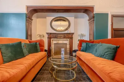 a living room with two orange couches and a glass table at Springbank Manor in Darwen