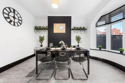 a dining room with a table and chairs and a clock at Luxury by the Sea, Beautiful 3 bedroom House with Fast WiFi, King Bed, Lovely Garden! Blackpool's Finest Getaway Experience for up to 8 Guests! in Blackpool