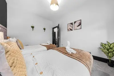 two beds in a room with white walls at Luxury by the Sea, Beautiful 3 bedroom House with Fast WiFi, King Bed, Lovely Garden! Blackpool's Finest Getaway Experience for up to 8 Guests! in Blackpool