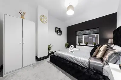 a bedroom with a large bed and a clock on the wall at Luxury by the Sea, Beautiful 3 bedroom House with Fast WiFi, King Bed, Lovely Garden! Blackpool's Finest Getaway Experience for up to 8 Guests! in Blackpool