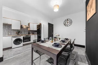 a large kitchen with a table and chairs in it at Luxury by the Sea, Beautiful 3 bedroom House with Fast WiFi, King Bed, Lovely Garden! Blackpool's Finest Getaway Experience for up to 8 Guests! in Blackpool