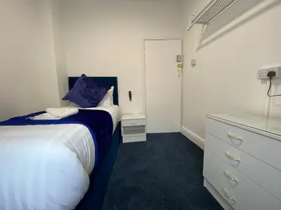 a small bedroom with a bed and a dresser at The New Athena Hotel in Blackpool
