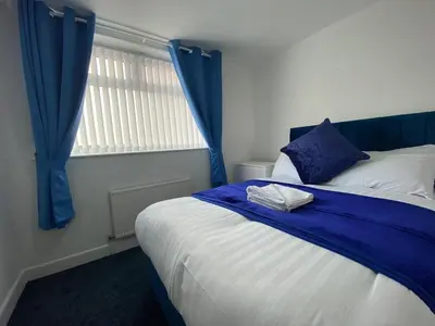 a bedroom with a bed with blue curtains and a window at The New Athena Hotel in Blackpool