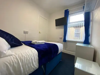 a bedroom with a bed with a blue blanket and a window at The New Athena Hotel in Blackpool