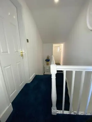 a stairway with a white door and a blue carpet at AQUARIUS APARTMENT - SEA VIEW - SLEEPS SEVEN in Blackpool