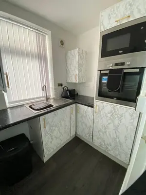 a small kitchen with a sink and a microwave at AQUARIUS APARTMENT - SEA VIEW - SLEEPS SEVEN in Blackpool