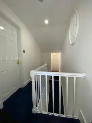 a white staircase with a white clock on the wall at AQUARIUS APARTMENT - SEA VIEW - SLEEPS SEVEN in Blackpool
