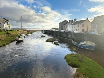 a river with boats in it with houses in the background at 23 Coastal Comfort in Millom