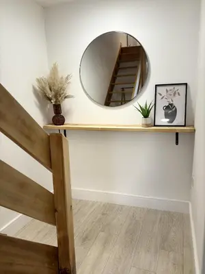a mirror on a wall with a wooden shelf at 23 Coastal Comfort in Millom