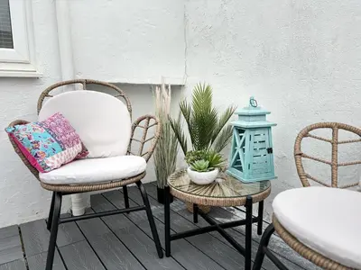 a patio with two chairs and a table with a lamp at 23 Coastal Comfort in Millom