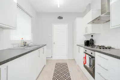 a white kitchen with white cabinets and a stove top oven at 4-Bed Contractor House Sleeps 7 Free Parking L20 Liverpool - Hosted by By Hinkley Homes Short Lets & Serviced Accommodation in Liverpool