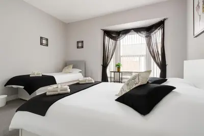 two beds in a white room with a window at 4-Bed Contractor House Sleeps 7 Free Parking L20 Liverpool - Hosted by By Hinkley Homes Short Lets & Serviced Accommodation in Liverpool