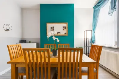 a dining room table with chairs and a blue wall at 4-Bed Contractor House Sleeps 7 Free Parking L20 Liverpool - Hosted by By Hinkley Homes Short Lets & Serviced Accommodation in Liverpool