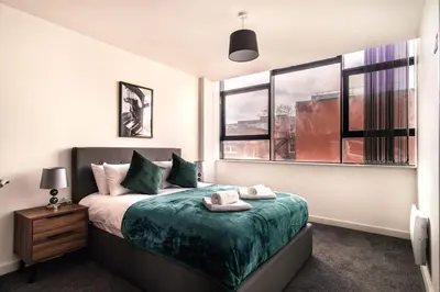 a bedroom with a bed with green sheets and windows at Contemporary 1 Bed Apartment in Central Preston in Preston