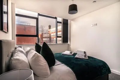 a bedroom with a bed with pillows and a large window at Contemporary 1 Bed Apartment in Central Preston in Preston