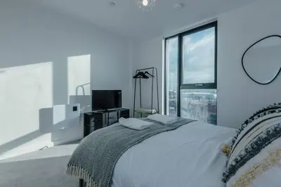 a white bedroom with a bed and a large window at Stunning 2-Bed Premium Apartment - Free WI-FI in Preston