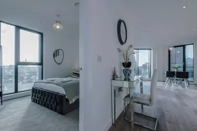 a bedroom with a bed and a room with windows at Stunning 2-Bed Premium Apartment - Free WI-FI in Preston