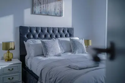 a bed with a blue headboard and pillows at Stunning 2-Bed Premium Apartment - Free WI-FI in Preston