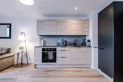a kitchen with white cabinets and a black appliance at Luxury King Size 1-Bed City Apartment - Free WI-FI in Preston