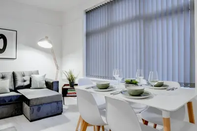 a white dining room with a white table and chairs at Stylish 2 bedroom flat - 15 minutes to Liverpool City Centre in Birkenhead