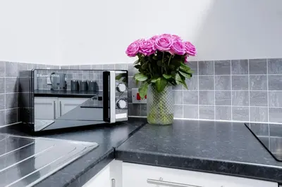 a vase filled with pink flowers on a kitchen counter at Stylish 2 bedroom flat - 15 minutes to Liverpool City Centre in Birkenhead