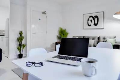 a laptop on a table with a cup of coffee and glasses at Stylish 2 bedroom flat - 15 minutes to Liverpool City Centre in Birkenhead