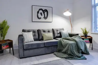 a living room with a gray couch with pillows at Stylish 2 bedroom flat - 15 minutes to Liverpool City Centre in Birkenhead