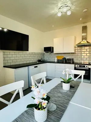 a kitchen with a table and chairs and a kitchen with white cabinets at Granada Apartments Holmfield Rd in Blackpool