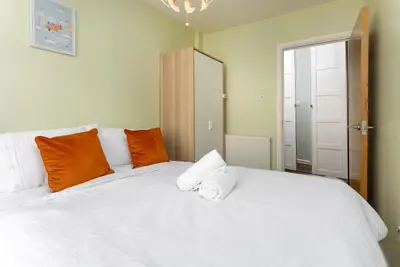 a bedroom with a white bed with orange pillows at Flatzy - 3 Bedroom Apartment in Heart of City Centre in Liverpool