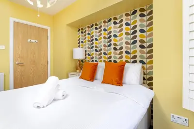 a bedroom with a white bed with orange pillows at Flatzy - 3 Bedroom Apartment in Heart of City Centre in Liverpool