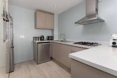 a white kitchen with a sink and a refrigerator at Flatzy - 3 Bedroom Apartment in Heart of City Centre in Liverpool