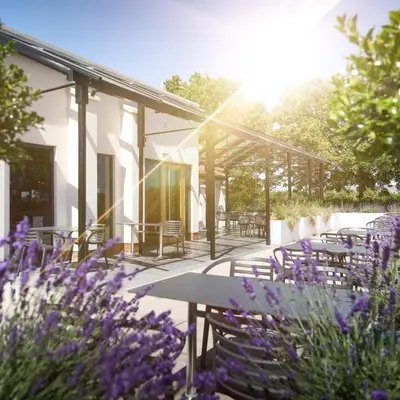 a patio with tables and chairs and purple flowers at Foxfields Country Hotel in Langho