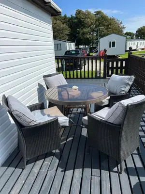 a patio with a table and chairs on a deck at Sunshine Lodge Haven Lakeland in Flookburgh