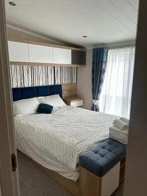 a bedroom with a large bed with a blue seat at Blissful Lodge Haven Lakeland in Flookburgh