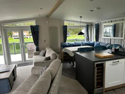 a living room with blue couches and a kitchen at Blissful Lodge Haven Lakeland in Flookburgh