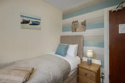 a bedroom with a bed with blue and white stripes at Arnside - Spacious 10-Bedroom Seaside Cottage in Blackpool