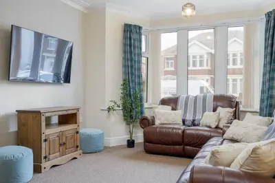 a living room with a couch and a tv at Arnside - Spacious 10-Bedroom Seaside Cottage in Blackpool