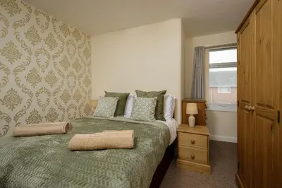 a bedroom with a green bed and a window at Arnside - Spacious 10-Bedroom Seaside Cottage in Blackpool