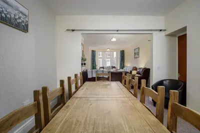 a dining room with a long table and chairs at Arnside - Spacious 10-Bedroom Seaside Cottage in Blackpool