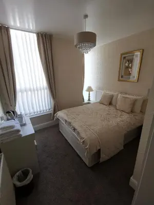 a bedroom with a large bed and a chandelier at The Stafford in Blackpool