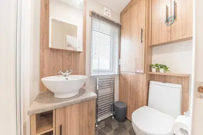 a bathroom with a white toilet and a sink at Tastefully decorated lodge on popular holiday park, easy access to Lakes and Dales and free parking in Carnforth