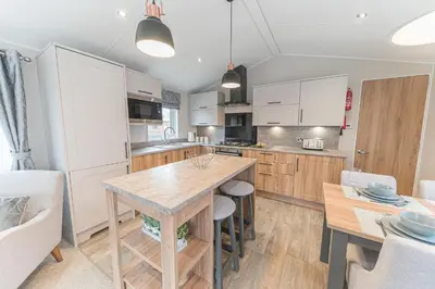 a kitchen with white cabinets and a wooden table at Tastefully decorated lodge on popular holiday park, easy access to Lakes and Dales and free parking in Carnforth